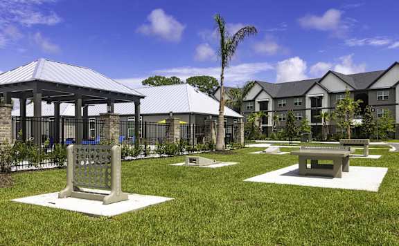 A gazebo is surrounded by benches and trees in a grassy area.
