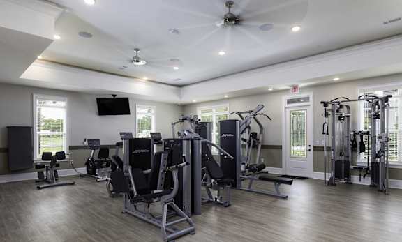 A spacious gym with a variety of equipment and a flat screen TV mounted on the wall.