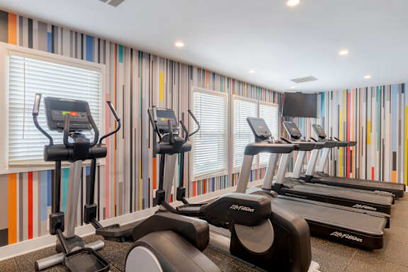 A row of treadmills in a gym with striped wallpaper.