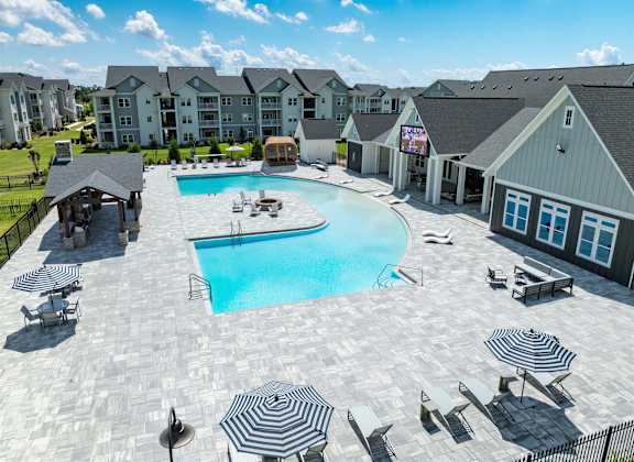 A large outdoor swimming pool surrounded by lounge chairs and umbrellas.