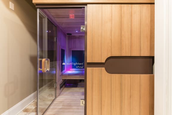 a wooden door with a black handle and a purple lighted room in the background
