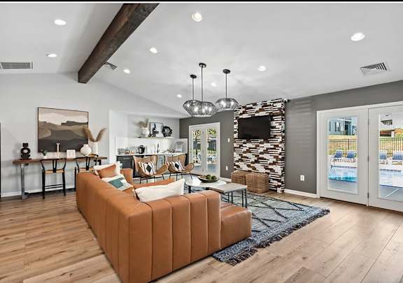 A living room with a brown sofa and a TV mounted on the wall.