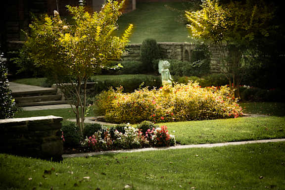 A garden with a statue and a yellow tree.
