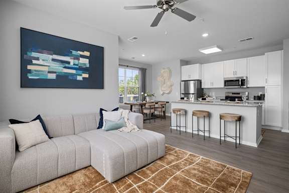 A modern living room with a grey sofa and a painting on the wall.