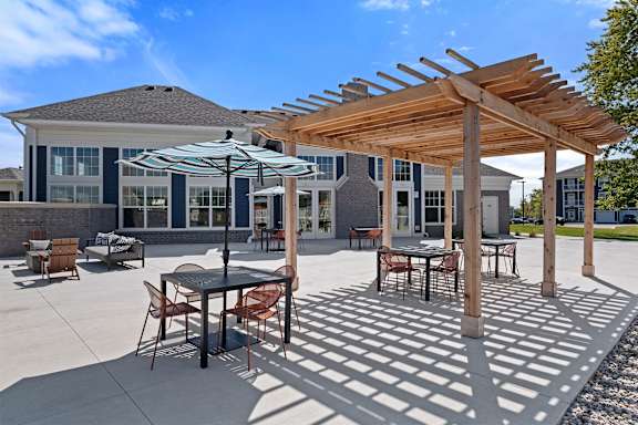 A patio with a table and chairs under a wooden pergola.