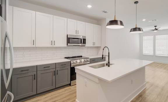 A modern kitchen with white and grey cabinets and a large island.
