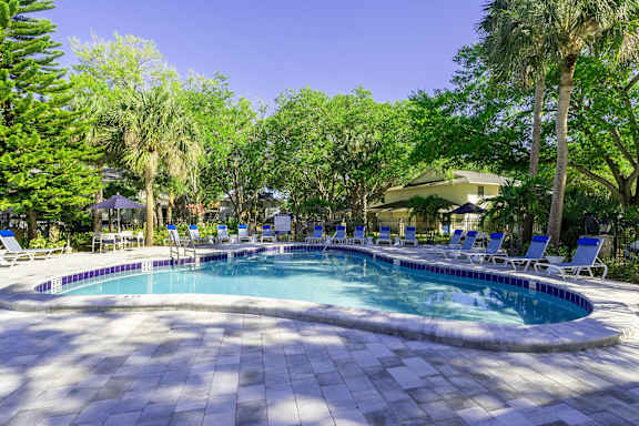 A round swimming pool surrounded by trees and chairs.