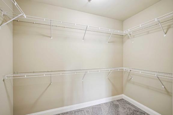 Empty white closet with shelves and hangers.