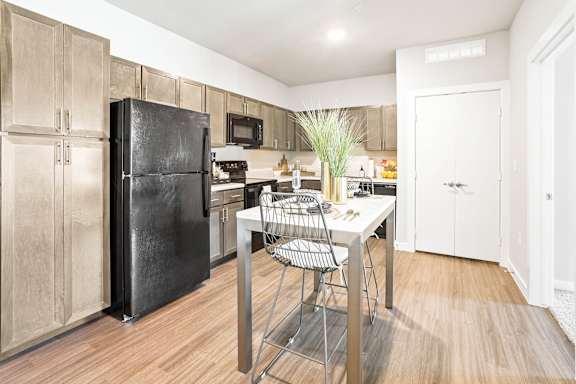 A kitchen with a black fridge and a white table.