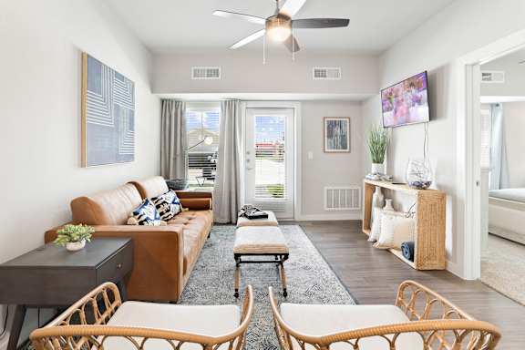 A living room with a brown couch and a ceiling fan.
