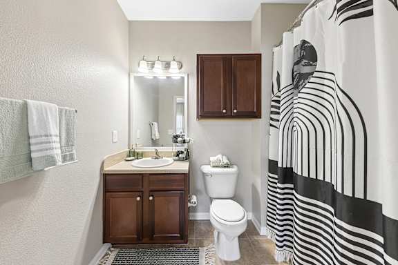 A bathroom with a sink, toilet, and a shower curtain with black and white stripes.