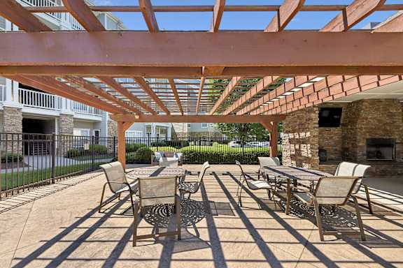 A patio with a table and chairs under a wooden pergola.
