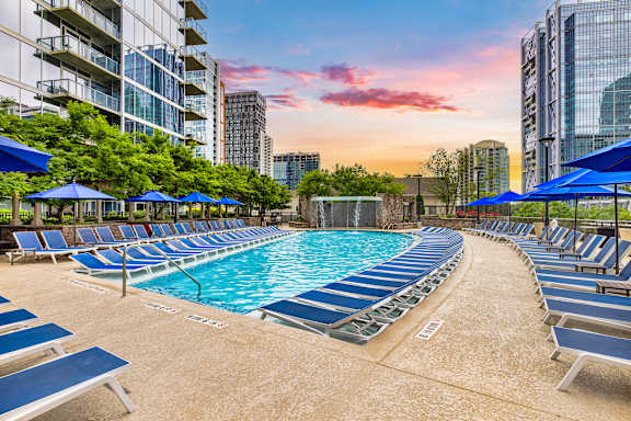 A swimming pool surrounded by blue lounge chairs and umbrellas.