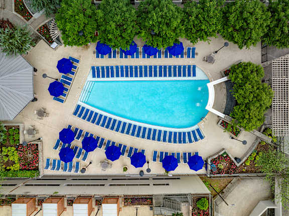 An aerial view of a pool surrounded by blue lounge chairs and umbrellas.