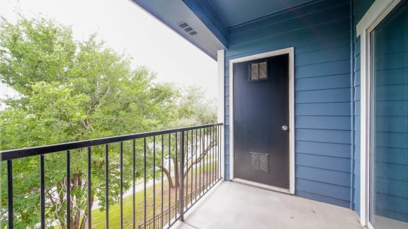 a balcony with a door to a blue building and a tree