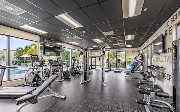A gym with a variety of equipment and a sign that says "Discipline, Achieve, Attractive, Healthier, Stronger".