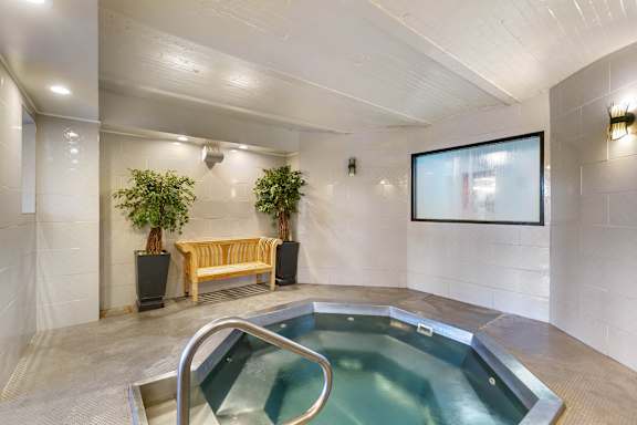 A hot tub in a room with a bench and plants.