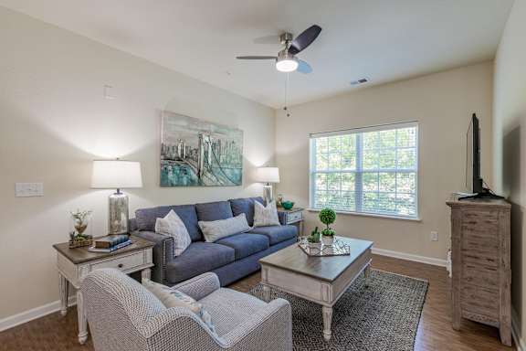 A living room with a grey couch, a coffee table, and a painting on the wall.