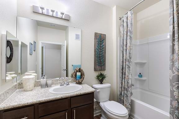 A bathroom with a white toilet, sink, and shower.
