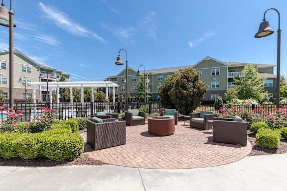 A sunny day at a courtyard with a fence, a pool, and a building in the background.