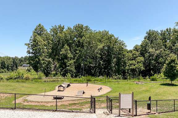 A playground with a swing set and a slide in the middle of a grassy area.