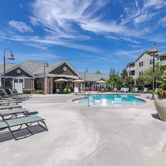 A large outdoor swimming pool surrounded by lounge chairs and umbrellas.