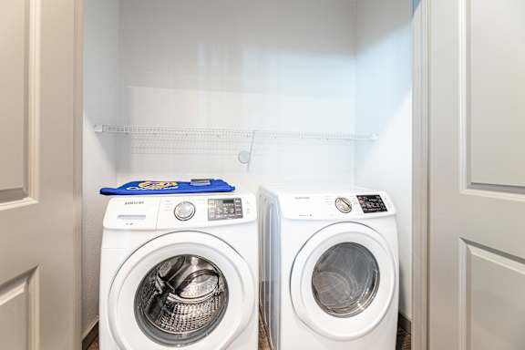 Two white washing machines in a laundry room.