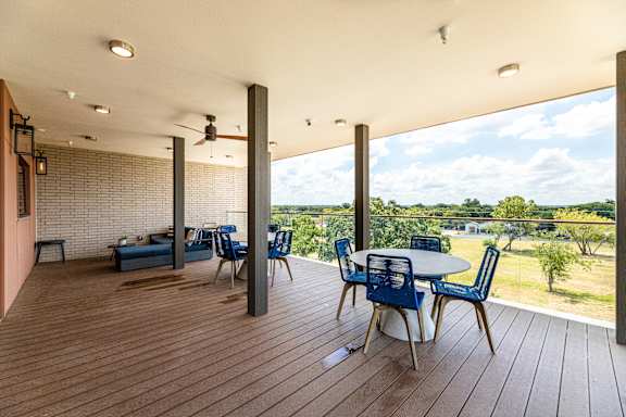 A wooden deck with a table and chairs overlooking a grassy area.