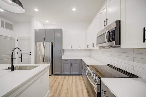 A modern kitchen with white cabinets and a wooden floor.