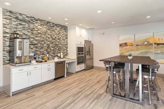 A modern kitchen with a stone wall and wooden flooring.