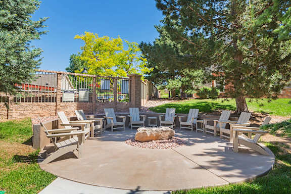 A fire pit is surrounded by chairs in a backyard.