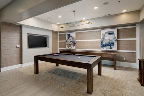 A pool table in a room with a television and a painting on the wall.