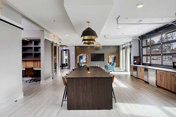 A modern kitchen with a long wooden island in the middle.