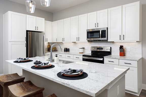 A kitchen with white cabinets and a marble countertop.