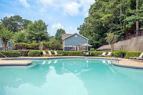 A swimming pool surrounded by trees and a house.