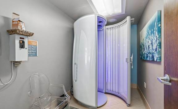 A room with a white circular machine and a basket on top of a shelf.