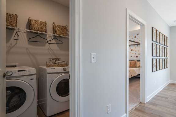 A laundry room with a washer and dryer and a doorway leading to a living room.