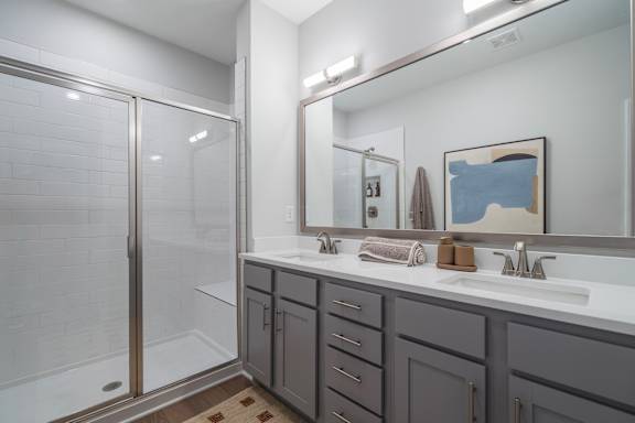 A bathroom with a white sink, a mirror, and a shower with a glass door.