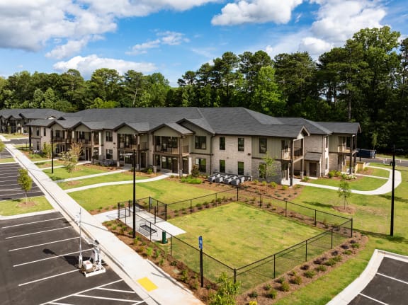 an aerial view of an apartment complex with a tennis court and lawn