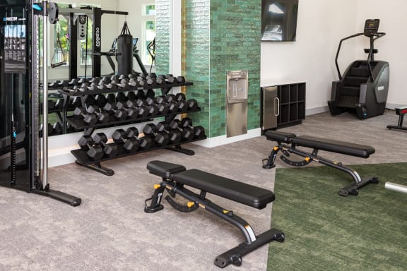 two views of a fitness room with weights and cardio equipment and a wall of mirrors