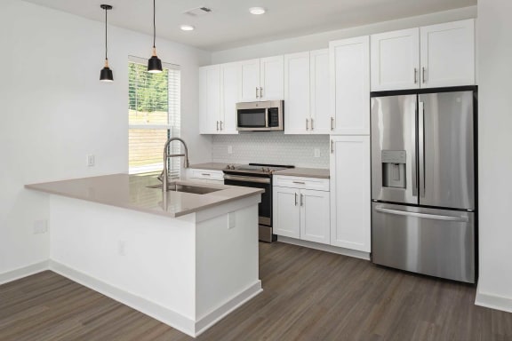 a white kitchen with stainless steel appliances and a counter top