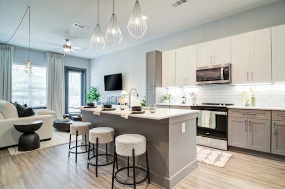 A modern kitchen with a bar area and a living room area.