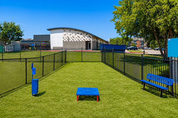 A park with a blue bench and a blue trash can.