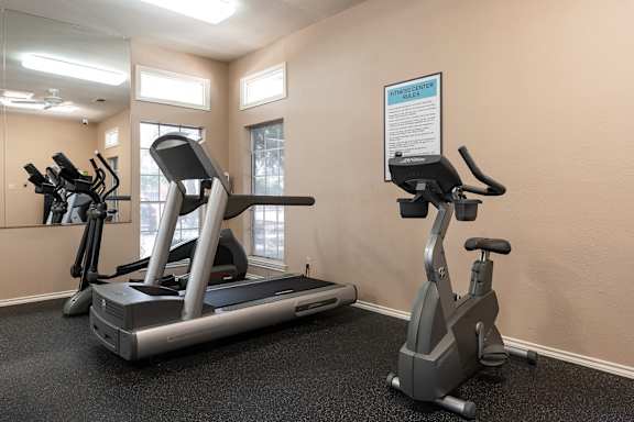 A gym with a treadmill and a stationary bike.
