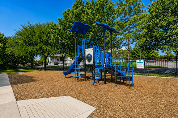 A playground with a blue slide and a brown surface.