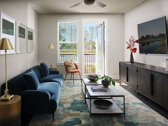 A living room with a blue couch and a television on the wall.