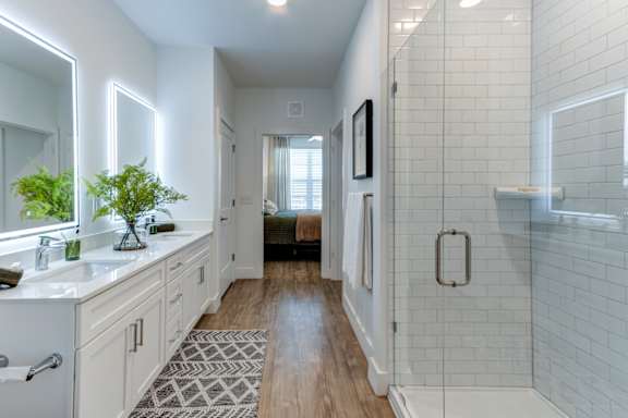 A bathroom with a white tile shower and a wooden floor.