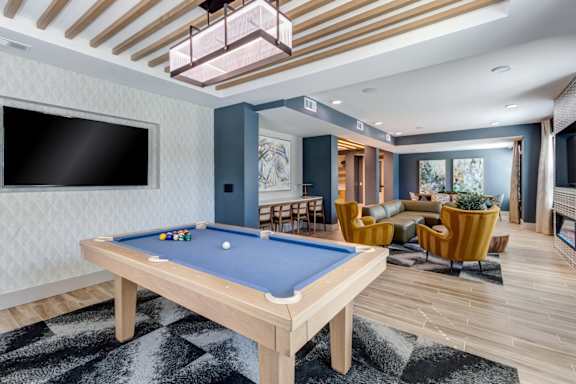 A pool table is in the middle of a room with a TV and a chair.