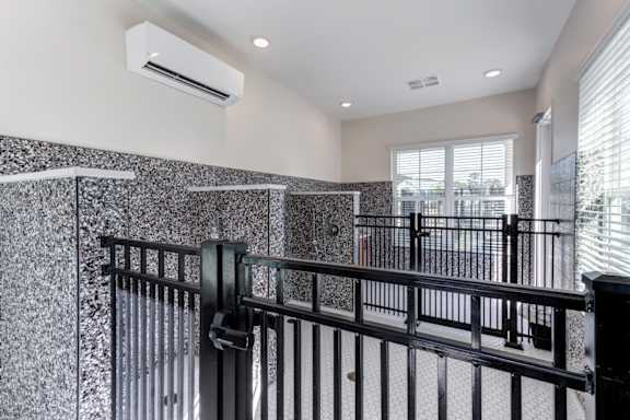 A black railing in a white room with a wall of windows.