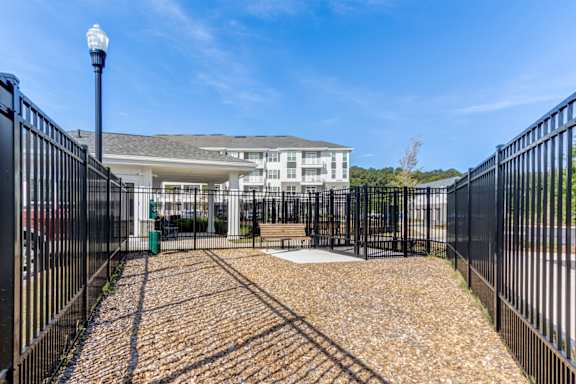 A black metal fence surrounds a gravel area in front of a white building.